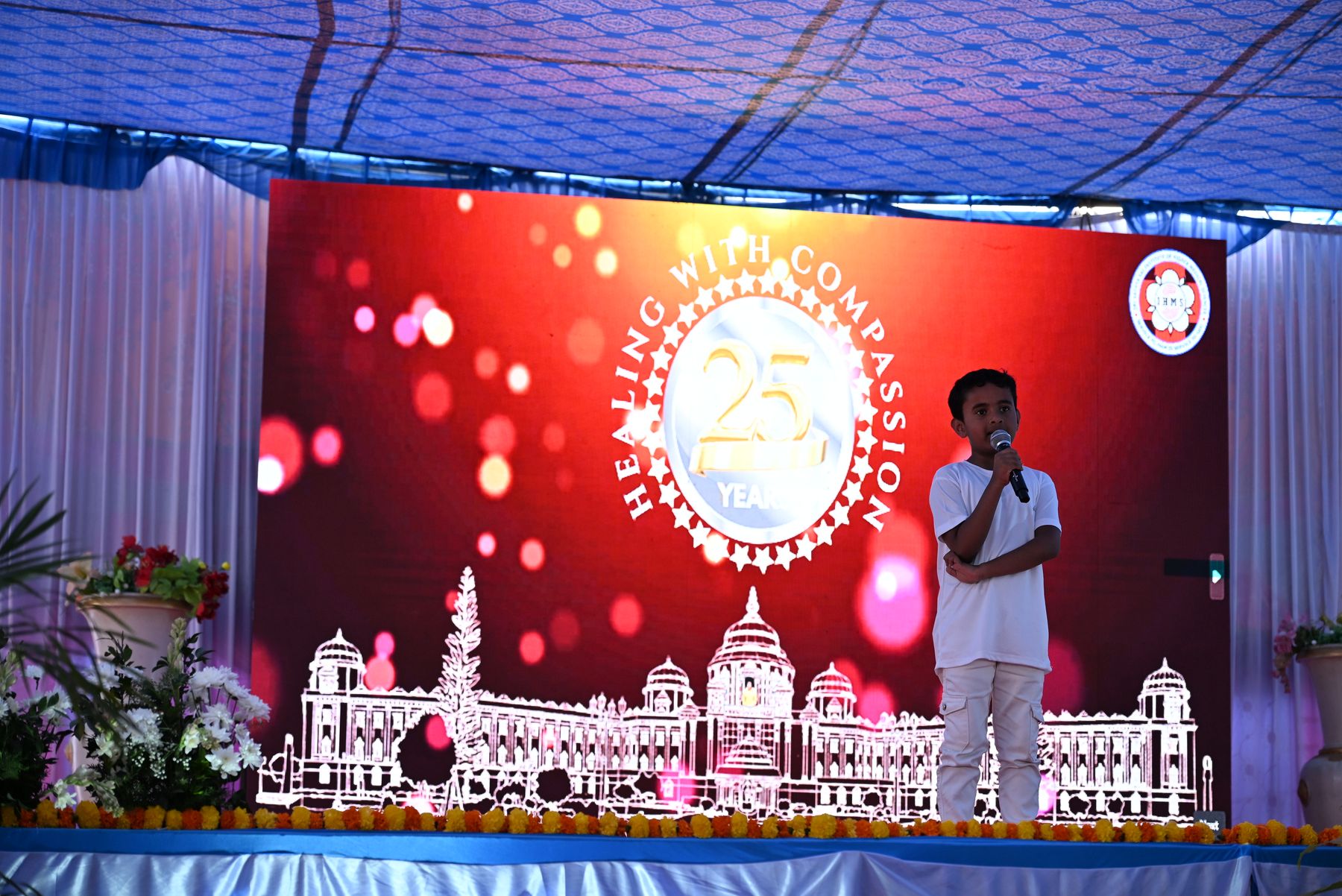 Child speaking on stage before the Healing with Compassion backdrop