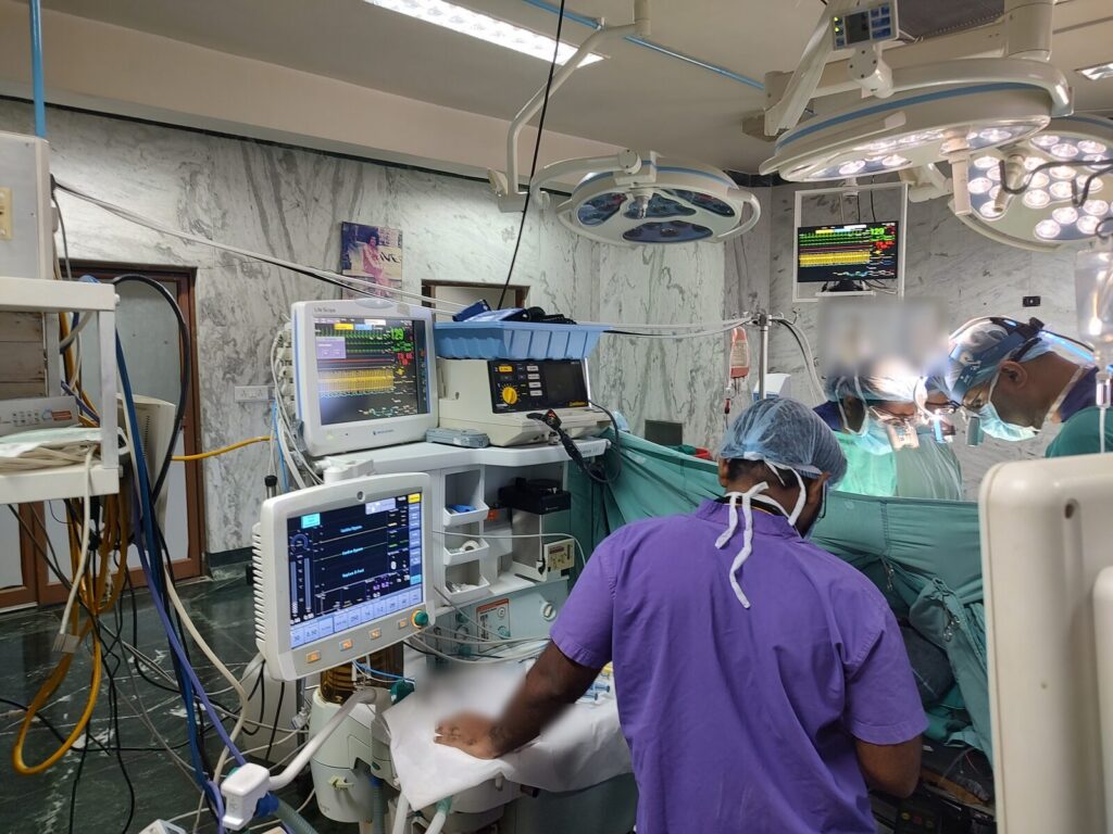 A theatre team member at the anaesthesia workstation and Nihon Kohden Life Scope monitors during open-heart surgery