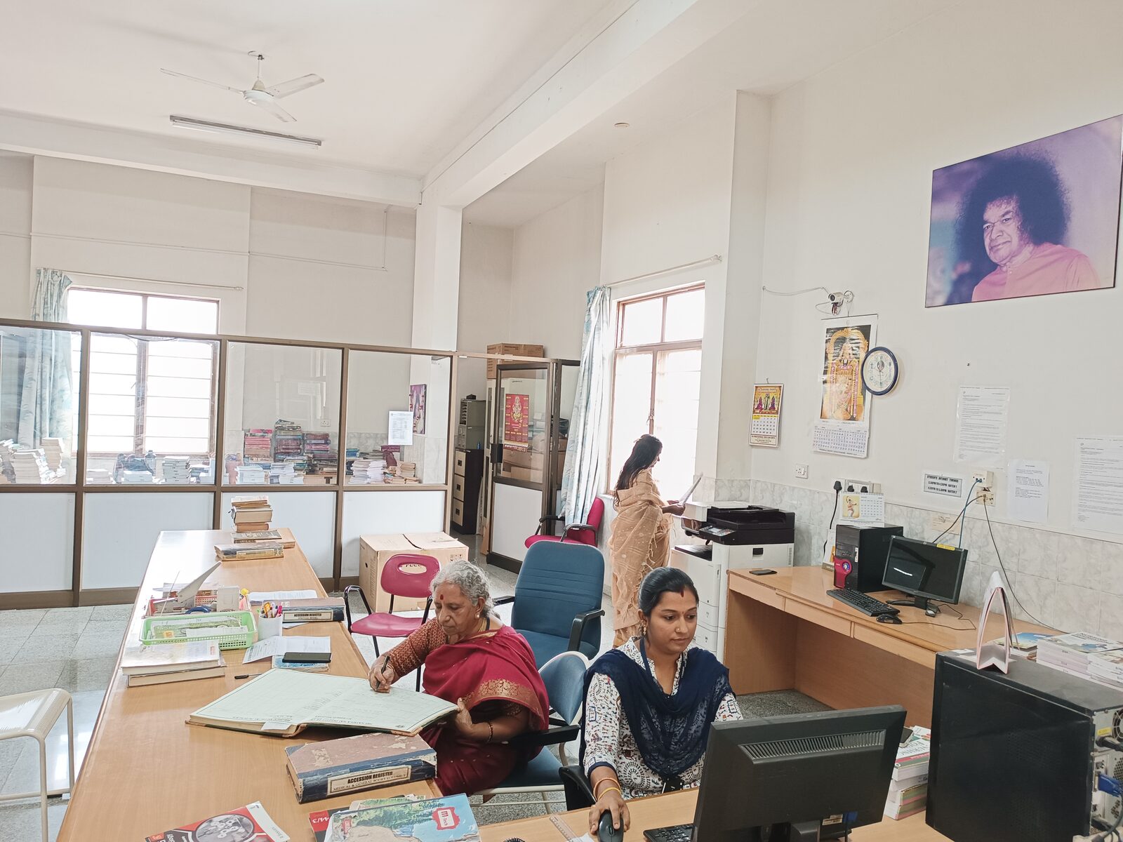 Library staff at the issue desk with the accession register